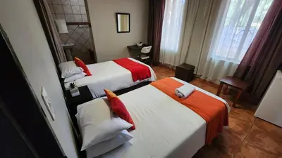 a hotel room with two beds with red and white sheets at Casa Feliz in Mokopane