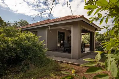 a small house with a porch in a garden at Impala Lily in Marloth Park