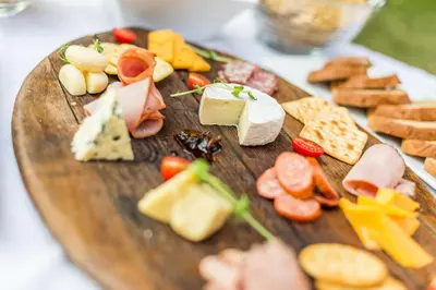 a wooden plate with different types of cheese and crackers at Sondela Nature Reserve & Spa Country House in Bela-Bela