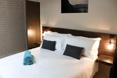 a bed with white sheets and pillows with a blue flower on it at The Ultimate Lodge in Louis Trichardt