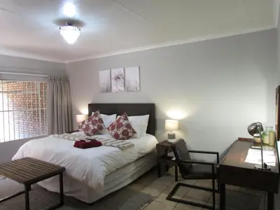 a bedroom with a bed and a desk and a chair at The Ultimate Lodge in Louis Trichardt