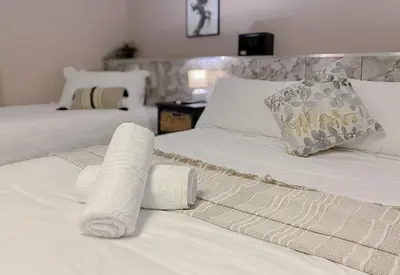 a bedroom with two beds with white sheets and pillows at The Ultimate Lodge in Louis Trichardt
