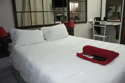 a white bed with a red bag on it at The Ultimate Lodge in Louis Trichardt
