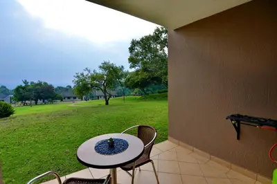 a patio with a table and chairs and a field at Crystal Springs Mountain Lodge in Pilgrimʼs Rest