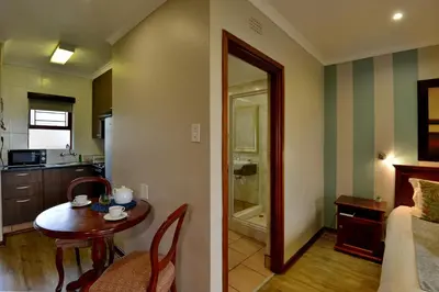 a living room with a table and a kitchen with a room at Crystal Springs Mountain Lodge in Pilgrimʼs Rest