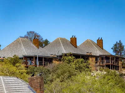 a large house with a roof on a hill at Crystal Springs Mountain Lodge in Pilgrimʼs Rest
