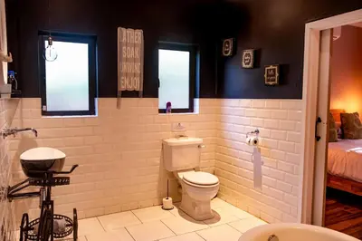 a bathroom with a toilet and a bed in a room at The Porcupine Porch in Marloth Park