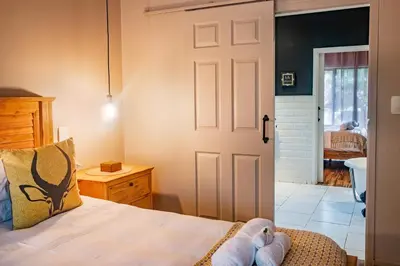 a bedroom with a bed and a door leading to a bathroom at The Porcupine Porch in Marloth Park