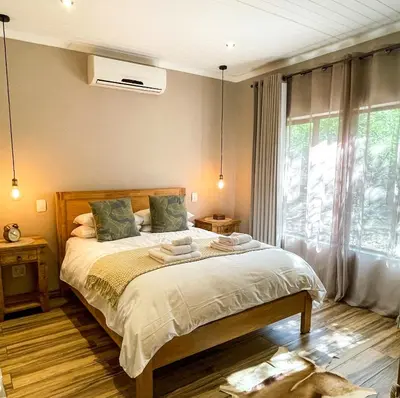 a bedroom with a bed and a large window at The Porcupine Porch in Marloth Park
