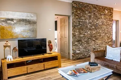 a living room with a television and a brick wall at The Porcupine Porch in Marloth Park