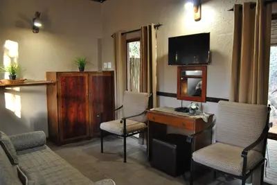 a living room with chairs and a desk and a television at Mabalingwe Elephant Lodge in Bela-Bela