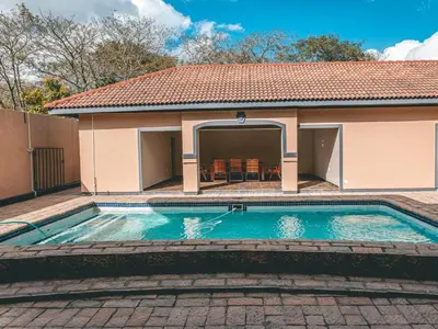 a swimming pool in front of a house at Khutso Boutique Hotel in Hazyview