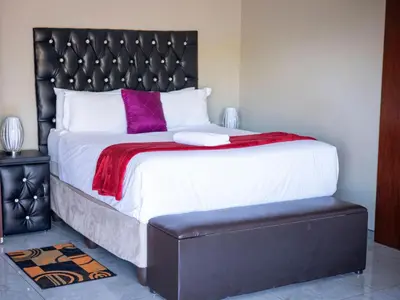 a bedroom with a large bed with a black headboard at Khutso Boutique Hotel in Hazyview