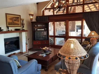 a living room with blue chairs and a fireplace at Kruger Park Lodge 401 in Hazyview