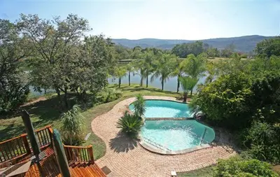 a swimming pool next to a river with trees at Kruger Park Lodge 401 in Hazyview