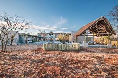 a house with a thatched roof in a yard at Kruger Sunset Lodge in Hectorspruit