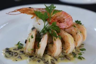 a white plate of shrimp with a garnishment at The Highlander Hotel Dullstroom in Dullstroom