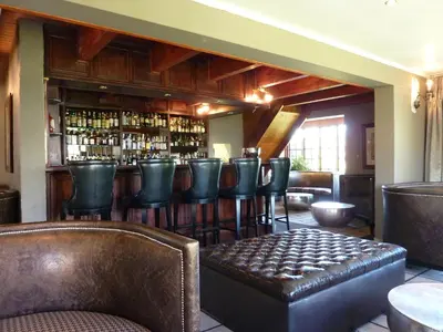 a bar with leather chairs and a shelf with liquor bottles at The Highlander Hotel Dullstroom in Dullstroom