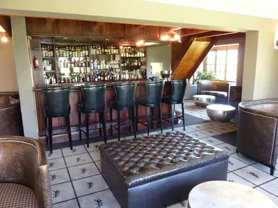 a bar with leather chairs and a bar stool at The Highlander Hotel Dullstroom in Dullstroom