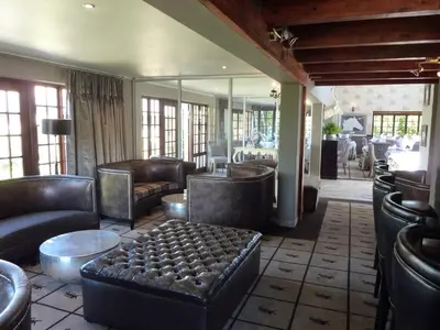 a lobby with leather couches and a table and mirrors at The Highlander Hotel Dullstroom in Dullstroom