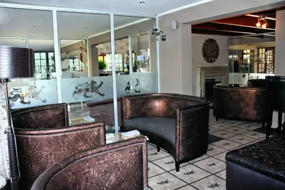 a restaurant with brown leather chairs and a mirror at The Highlander Hotel Dullstroom in Dullstroom