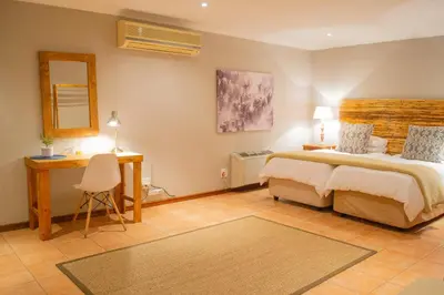 a bedroom with a bed and a desk and a mirror at Safari Club Guest Lodge OR Tambo International Airport in Kempton Park