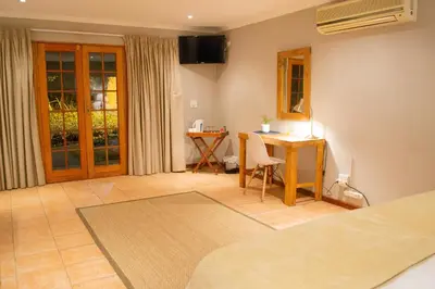 a room with a bed and a desk and a table at Safari Club Guest Lodge OR Tambo International Airport in Kempton Park