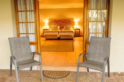 a living room with a bed and two chairs at Safari Club Guest Lodge OR Tambo International Airport in Kempton Park