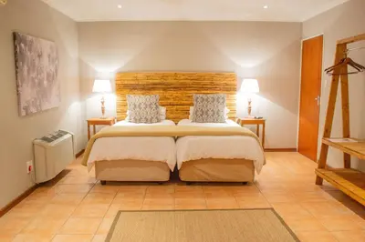 a bedroom with a large bed and two lamps at Safari Club Guest Lodge OR Tambo International Airport in Kempton Park