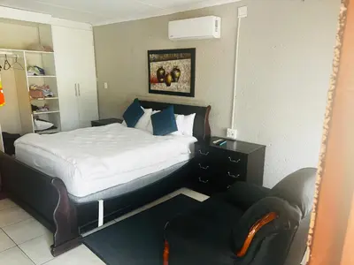 a bedroom with a bed and a chair and a mirror at BTV Guesthouse in Hazyview