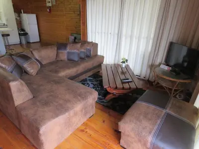 a living room with brown couches and a television at Viewpoint Lodge & Safari Tours in Hazyview