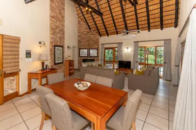 a dining room and living room with a table and chairs at Kruger Park Lodge Unit No 252 with private pool in Hazyview