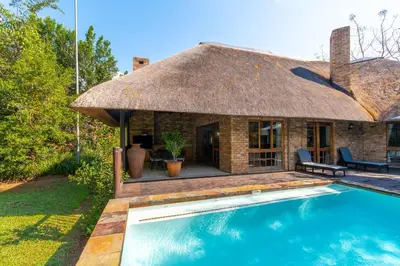 a house with a thatched roof and a swimming pool at Kruger Park Lodge Unit No 252 with private pool in Hazyview