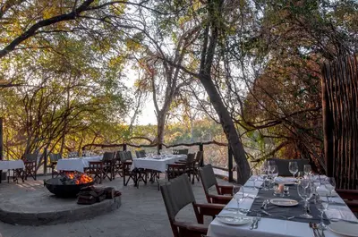 a restaurant with tables and chairs and a fire pit at Jock Safari Lodge in Skukuza
