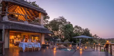 a restaurant with tables and umbrellas on a deck at Jock Safari Lodge in Skukuza