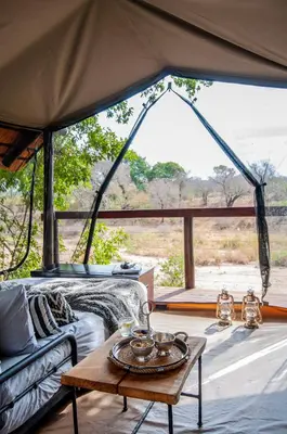 a room with a bed and a table in a tent at Jock Safari Lodge in Skukuza