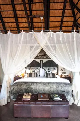 a bedroom with a large bed with white drapes at Jock Safari Lodge in Skukuza