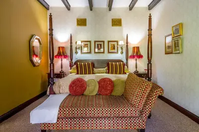 a bedroom with a bed with a couch and two lamps at Kilmorna Manor Guest House in Schoemanskloof