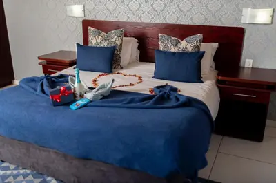 a bedroom with a bed with blue sheets and blue pillows at Ritsako Game Lodge in Klipdrift