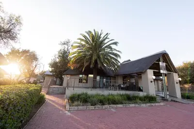 a house with a palm tree in front of it at Ritsako Game Lodge in Klipdrift