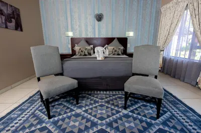 a bedroom with a bed and two chairs in it at Ritsako Game Lodge in Klipdrift