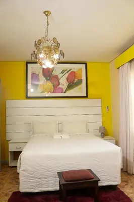 a bedroom with a white bed and a chandelier at Mamli Guestlodge & Conferencing in Schoemansdal