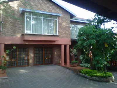a brick building with a large window and a tree at Mamli Guestlodge & Conferencing in Schoemansdal