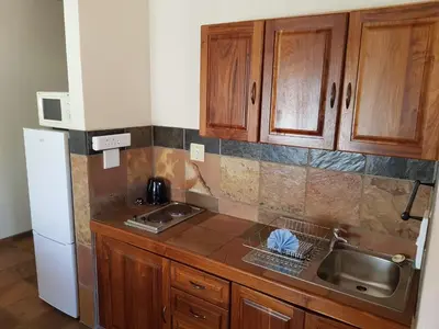 a kitchen with wooden cabinets and a sink and a refrigerator at Blyde Canyon, A Forever Resort in Matibidi