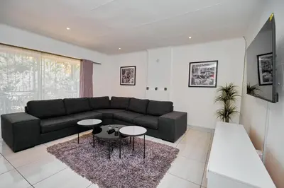 a living room with a black couch and two tables at Menlyn Maine: The Exquisite Lunette in Pretoria