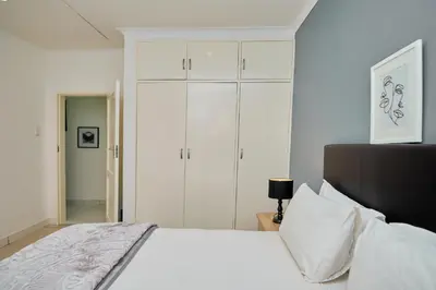 a bedroom with a white bed and white cabinets at Menlyn Maine: The Exquisite Lunette in Pretoria