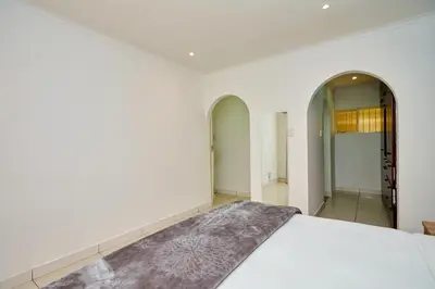 a bedroom with a white bed and a mirror at Menlyn Maine: The Exquisite Lunette in Pretoria