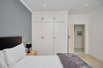 a white bedroom with a bed and white cabinets at Menlyn Maine: The Exquisite Lunette in Pretoria