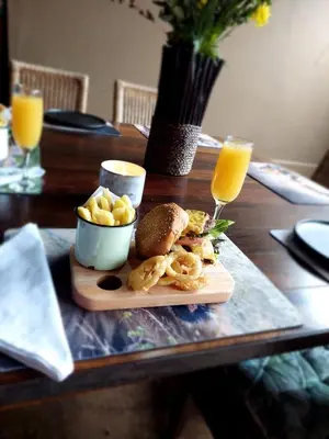 a wooden table with a plate of food and orange juice at Dar Amane Guest House in Graskop