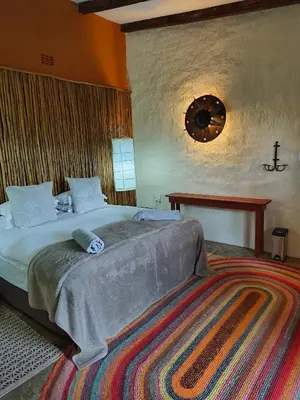 a bedroom with a large bed and a table at Dar Amane Guest House in Graskop